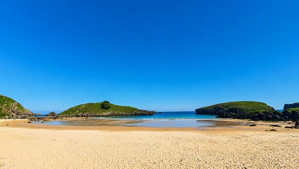 A beach with clear blue water, sandy shore, and green hills in the background. - Villa Playa de Barro with garden - Llanes (Llanes)