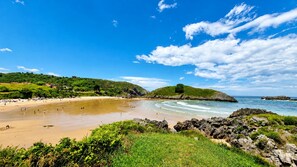 A coastal beach with rocky outcrops, a sandy shore, and green hills in the background. - Villa Playa de Barro with garden - Llanes (Llanes)