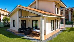 A modern two-story house with a covered patio, outdoor seating, and a well-maintained lawn. - Villa Playa de Barro with garden - Llanes (Llanes)