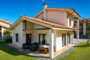 A modern two-story house with a covered patio, outdoor seating, and a well-maintained lawn. - Villa Playa de Barro with garden - Llanes (Llanes)
