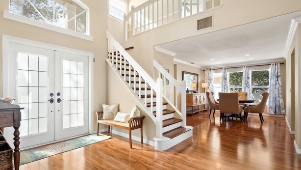 Un intérieur spacieux avec un escalier en bois, un coin repas et de grandes fenêtres.