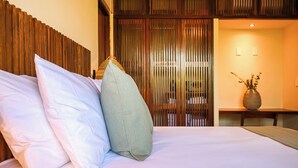 A bed with white and grey pillows, a wooden headboard, and a wooden partition in the background. - Luxury Apartment in Botánic Tulum 2 Br (Tulum)