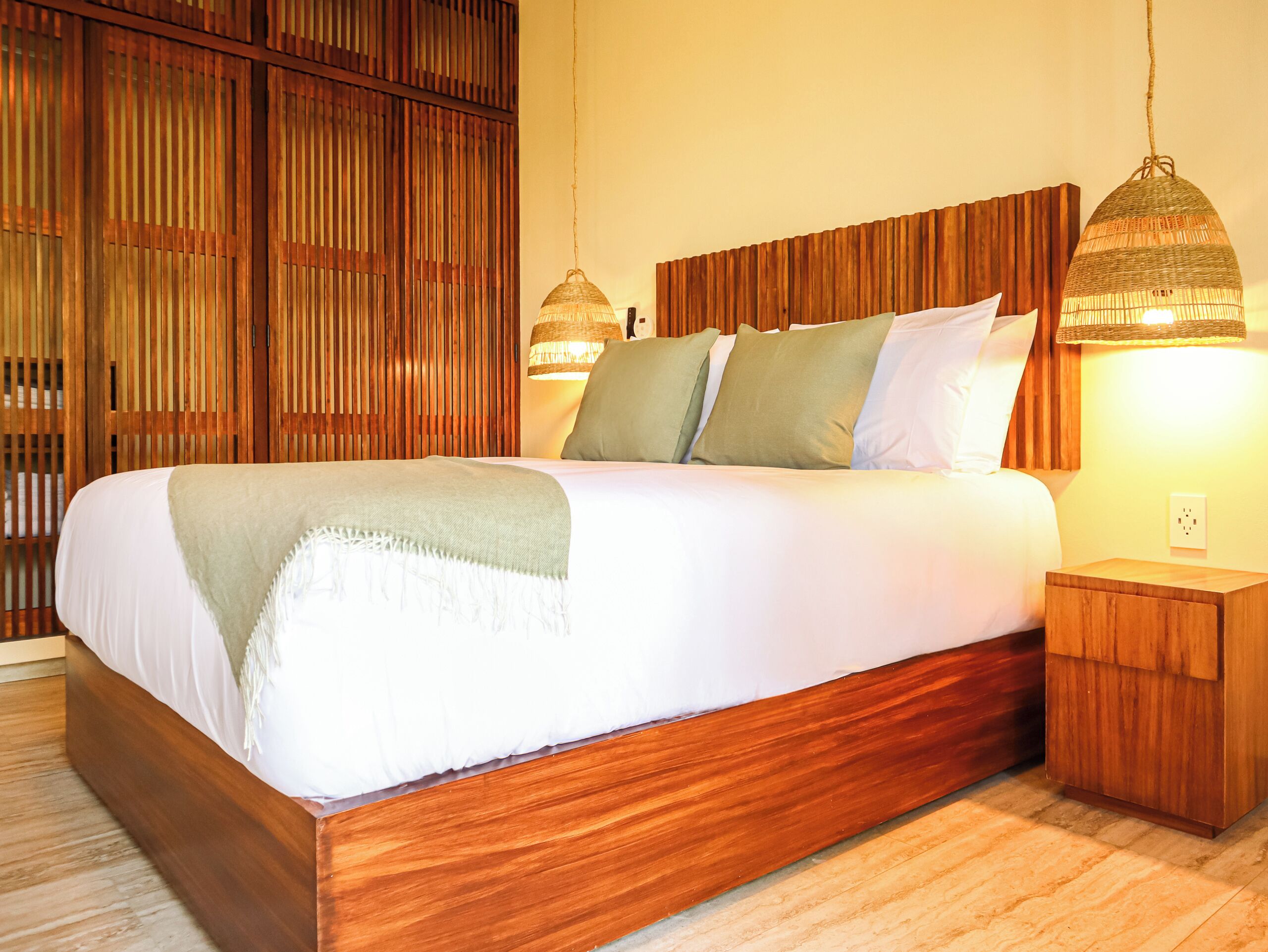 A large bed with a wooden headboard and footboard, flanked by two nightstands with lamps.