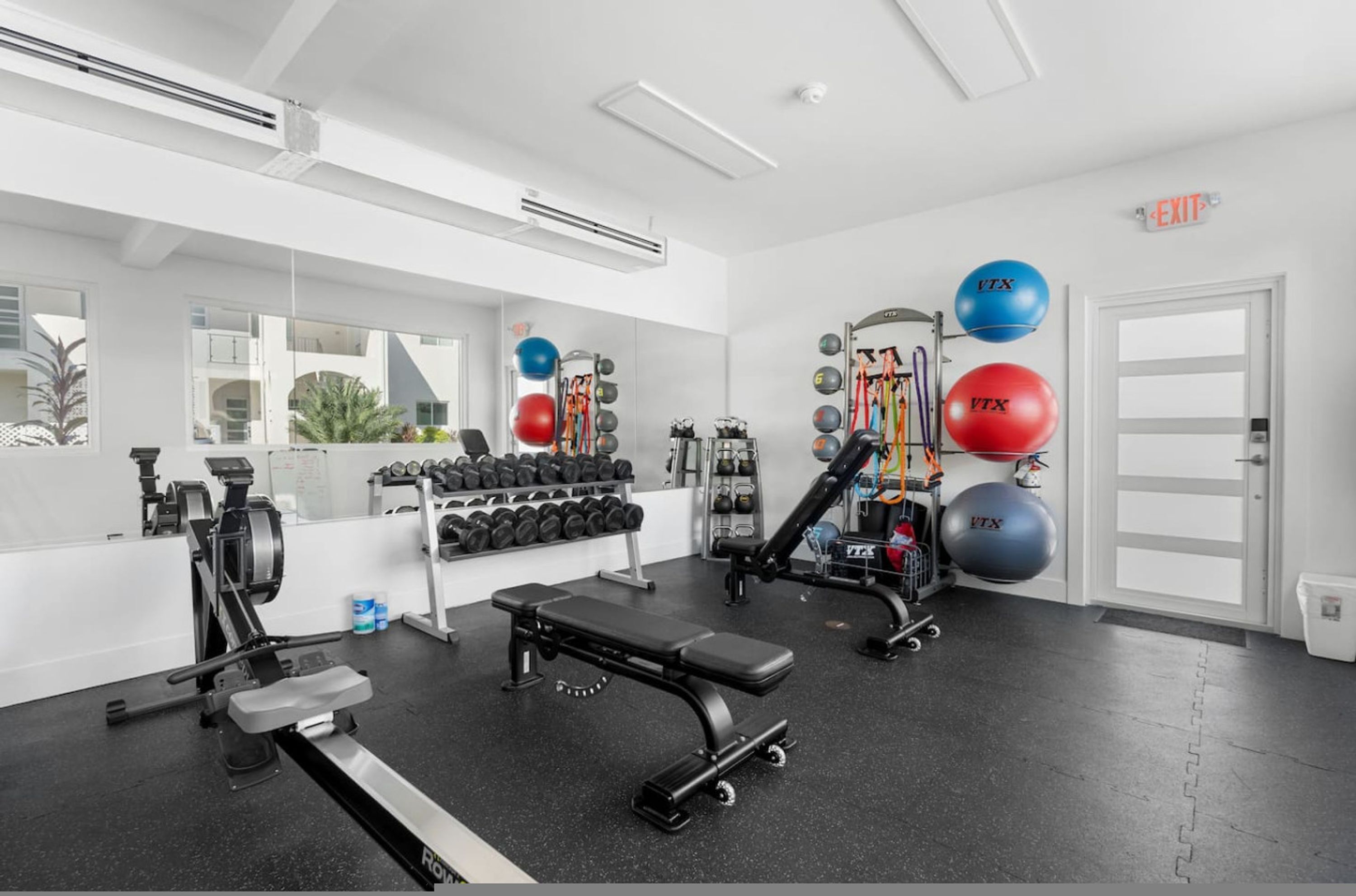 Un gimnasio con equipo de ejercicio, mancuernas y pelotas de entrenamiento.