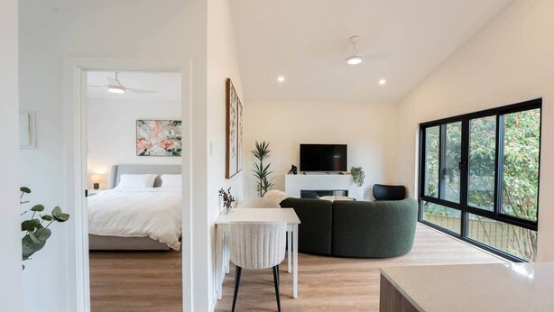 Une chambre à coucher moderne avec un lit, une table de chevet et une grande fenêtre.