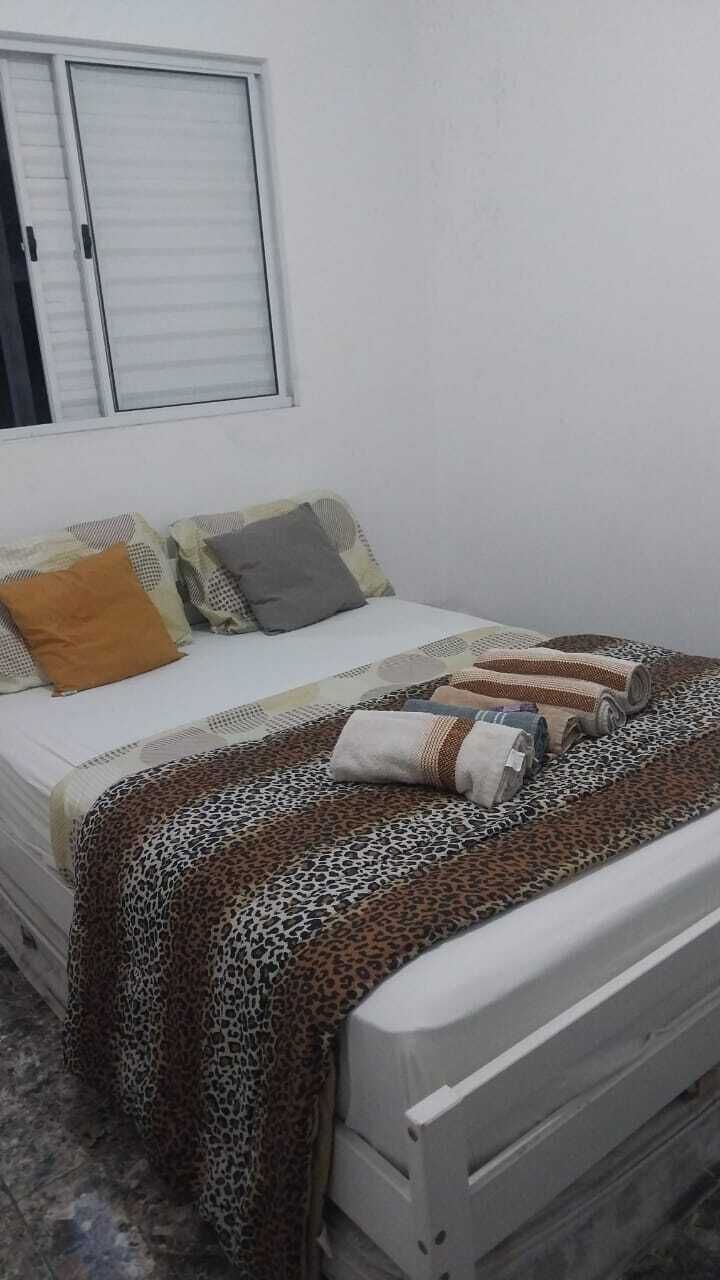 Ein Schlafzimmer mit einem Bett, Kissen, einem Fenster und einer Decke mit Leopardenmuster.