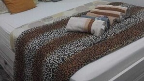 A bedroom with a bed, pillows, a window, and a leopard print blanket. - APTO Granja Vianna Brand New (Cotia)