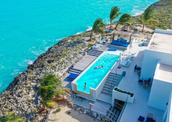 A rooftop pool with a view of the ocean, a covered seating area, and a staircase leading to the pool.