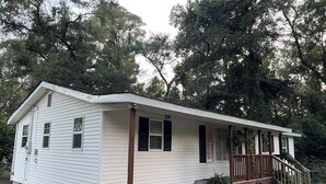 A single-story house with a front porch, a small staircase, and a front yard.