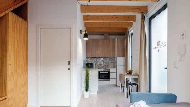 Une chambre d’hôtel moderne avec un plafond en bois, une kitchenette, un coin repas et un lit avec une serviette roulée.