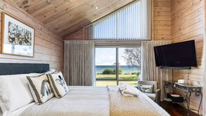 Un dormitorio con una cama grande, televisión y vistas al mar.