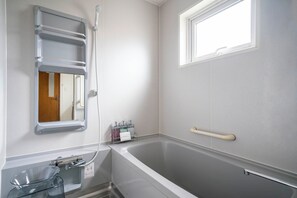 A bathroom with a bathtub, a window, a towel rack, and a glass container. - CRAFT (Asahikawa)