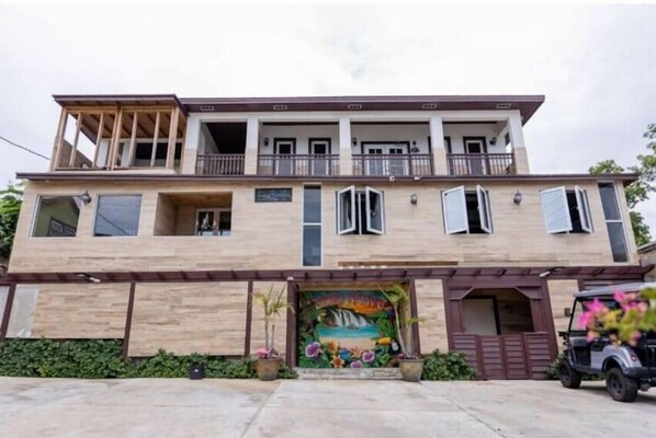A two-story building with a balcony on the upper floor, a mural at the entrance, and a parked vehicle in front. - Simply Native B And B (Nassau)