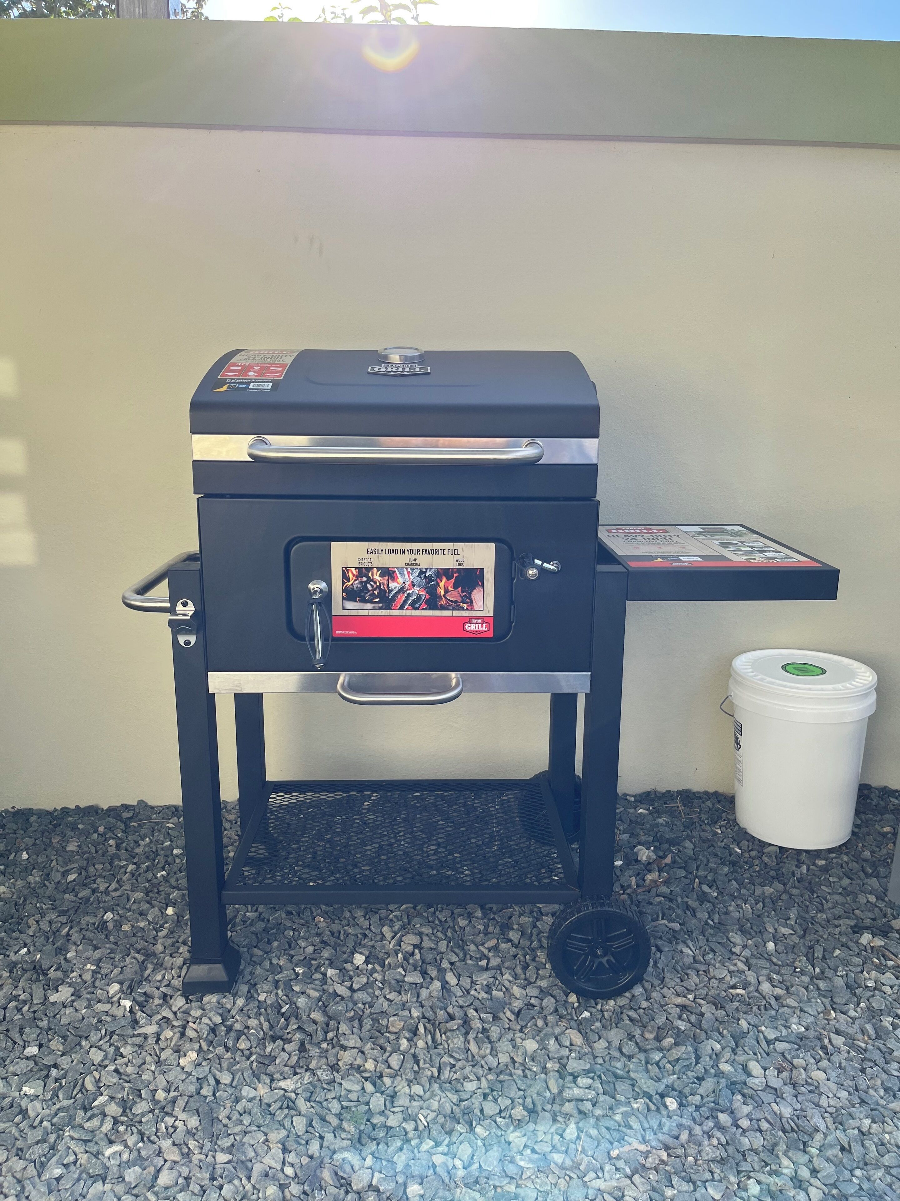 A barbecue grill with a fuel container beside it.