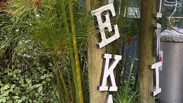 A wooden post with letters spelling "WEKA" and a black decorative item attached to it.