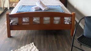 A bedroom with a wooden bed, a nightstand, a dresser, and a chair. - Weka cabin, great views (Wainui)