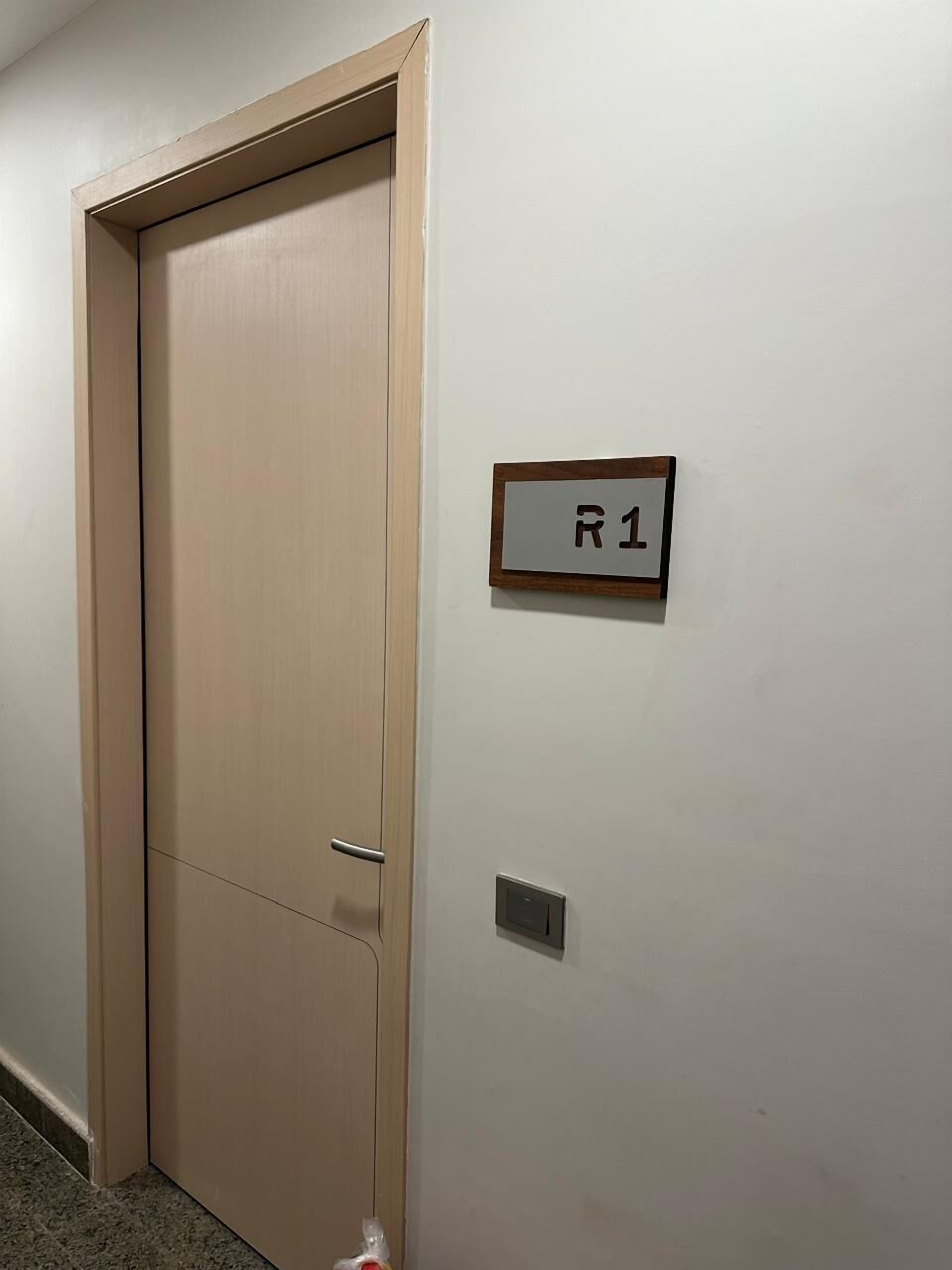 A closed door with a sign reading "R1" on the adjacent wall.