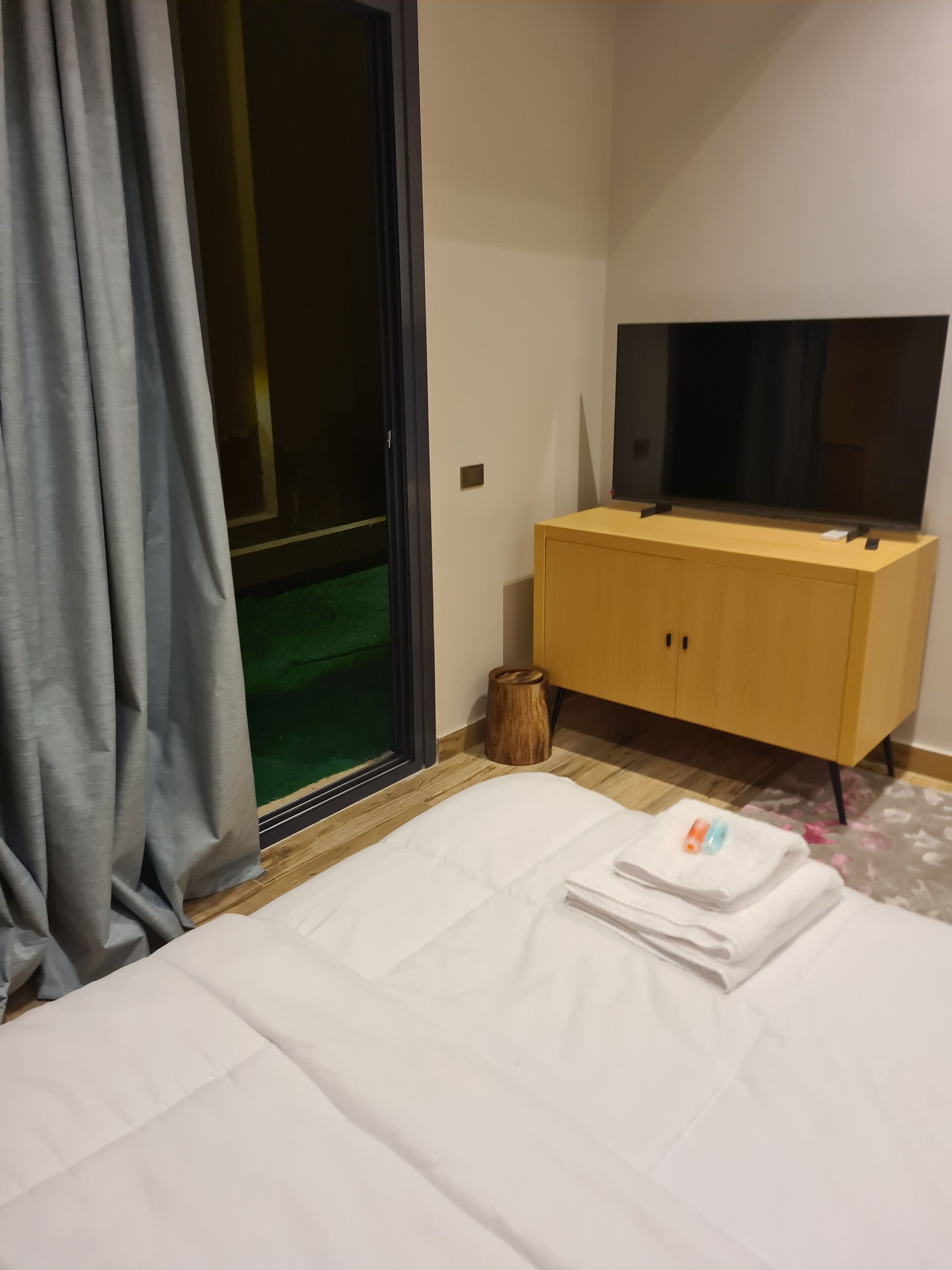 Una habitación de hotel con una cama, un armario de madera, un televisor y una ventana con cortinas.