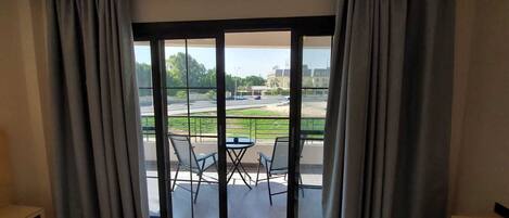 Et værelse med en stor skydedør, der fører ud til en balkon med to stole og et bord.