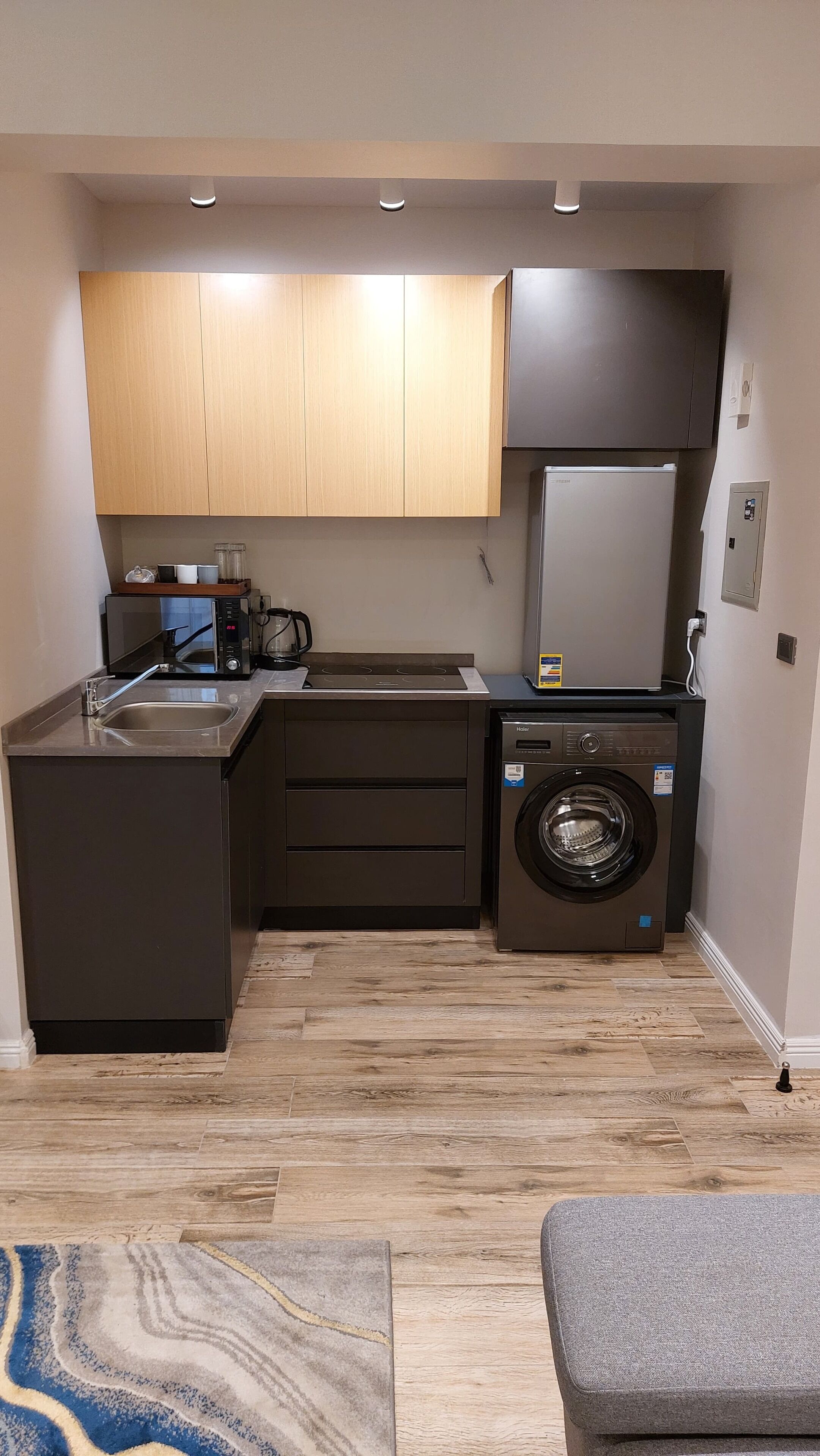 Una cocina compacta con lavadora integrada, microondas y fregadero.