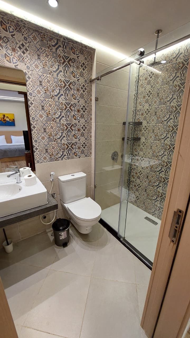 Une salle de bain moderne avec des carreaux à motifs, une douche en verre, des toilettes et un lavabo avec un miroir.