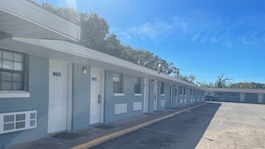 A row of motel rooms with individual doors, a parking lot, and a clear blue sky. - Western Skies Motel (Seagoville)