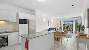 Una cocina moderna con armarios blancos, encimera de granito y un comedor con mesa y sillas.