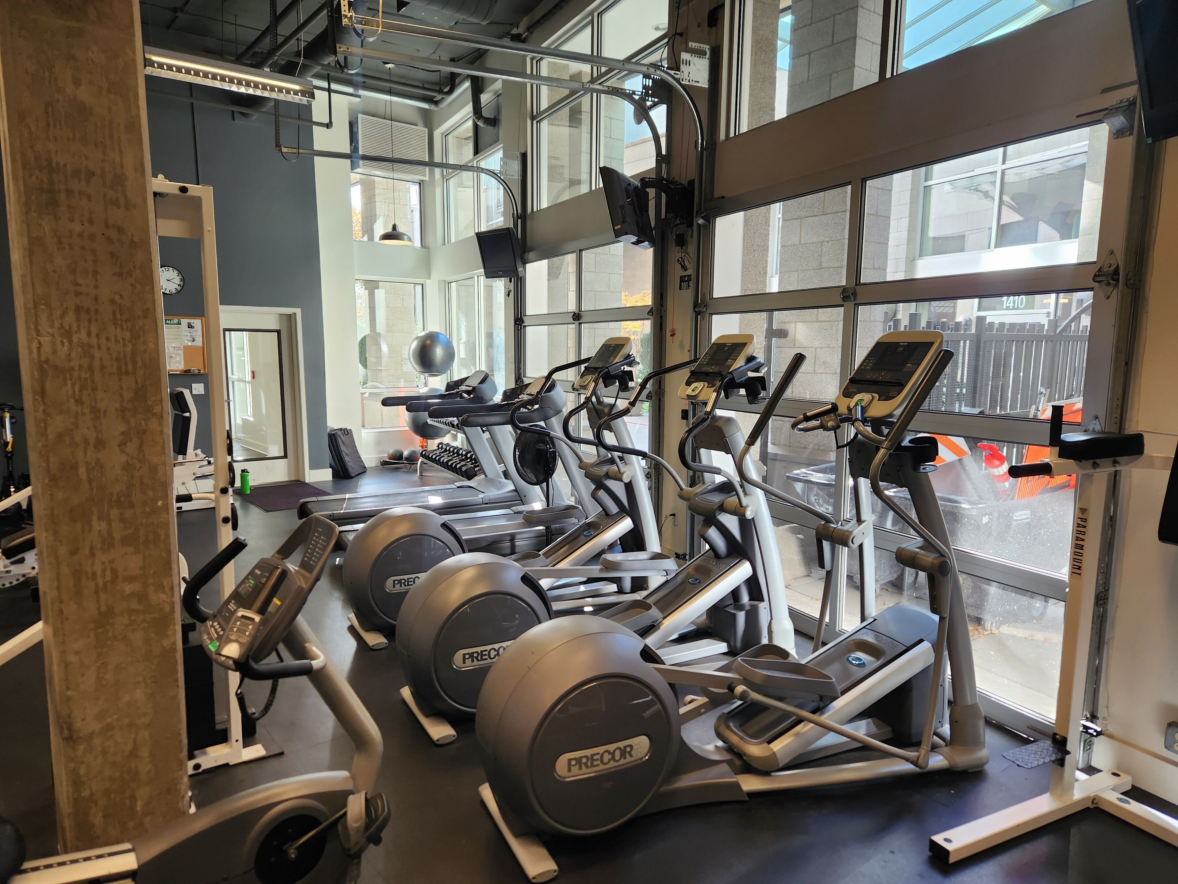 A gym with treadmills, elliptical machines, and weight plates.