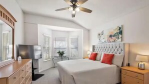 A bedroom with a bed, a nightstand, a TV, and a ceiling fan. - The Disney & Universal Dog House - Fenced Yard (Davenport)