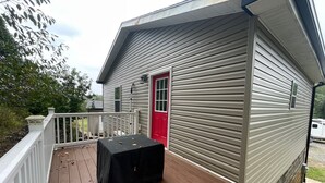 Una terraza de madera con una mesa y una puerta roja.