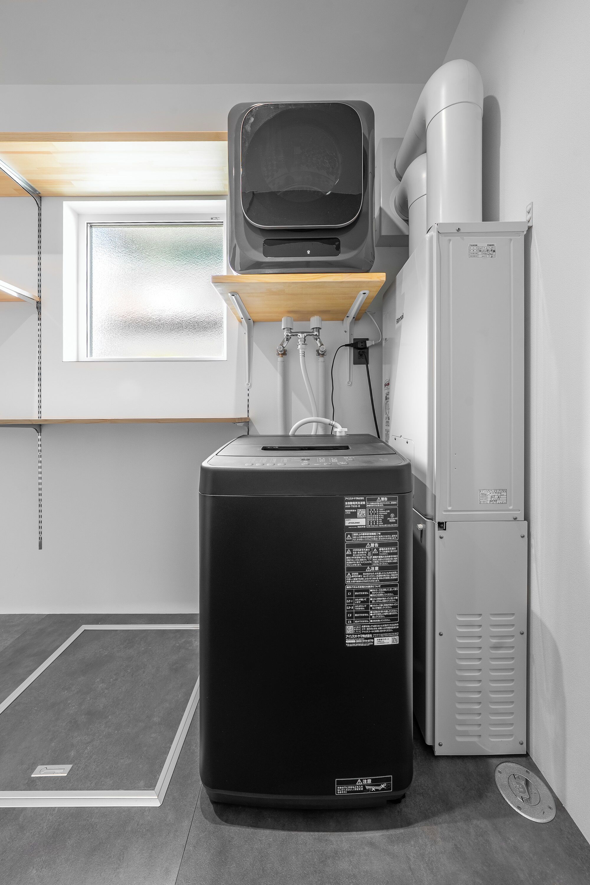 A compact kitchenette with a microwave, a small refrigerator, and a window with blinds.