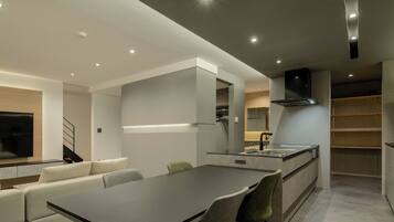 A modern kitchen with a central island, built-in appliances, and a dining area with a sofa and chairs.