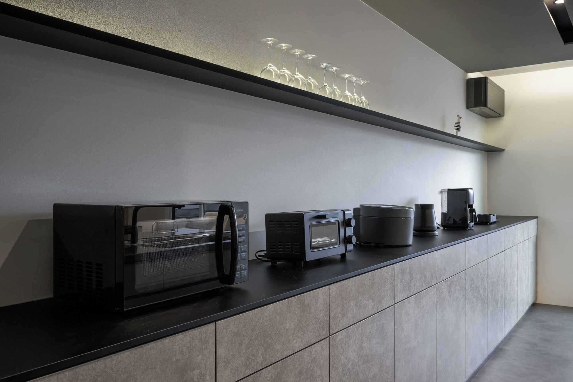Une cuisine moderne dotée d’un four à micro-ondes, d’une machine à café et d’autres appareils électroménagers, le tout installé sur un plan de travail élégant.