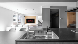A modern kitchen with a large island, built-in appliances, and a flat-screen TV displaying 'NETFLIX'. - S suzukou (Asahikawa)