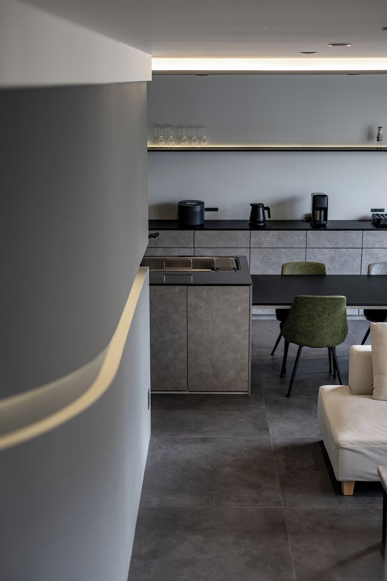 Una cocina moderna con una isla integrada, una zona de comedor con mesa y sillas, y un sofá.