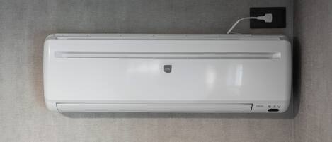 Aire acondicionado de pared con cable conectado, sobre un muro texturizado.