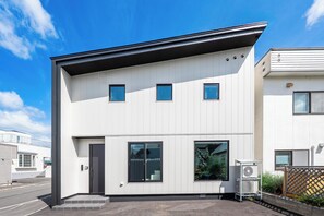 A modern building with a flat roof, a central entrance, and a small air conditioning unit outside. - S suzukou (Asahikawa)