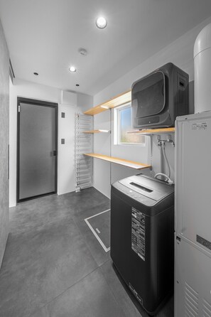 A compact kitchen with a refrigerator, microwave, and built-in oven. There is a window providing natural light and a door leading to another room. - S suzukou (Asahikawa)