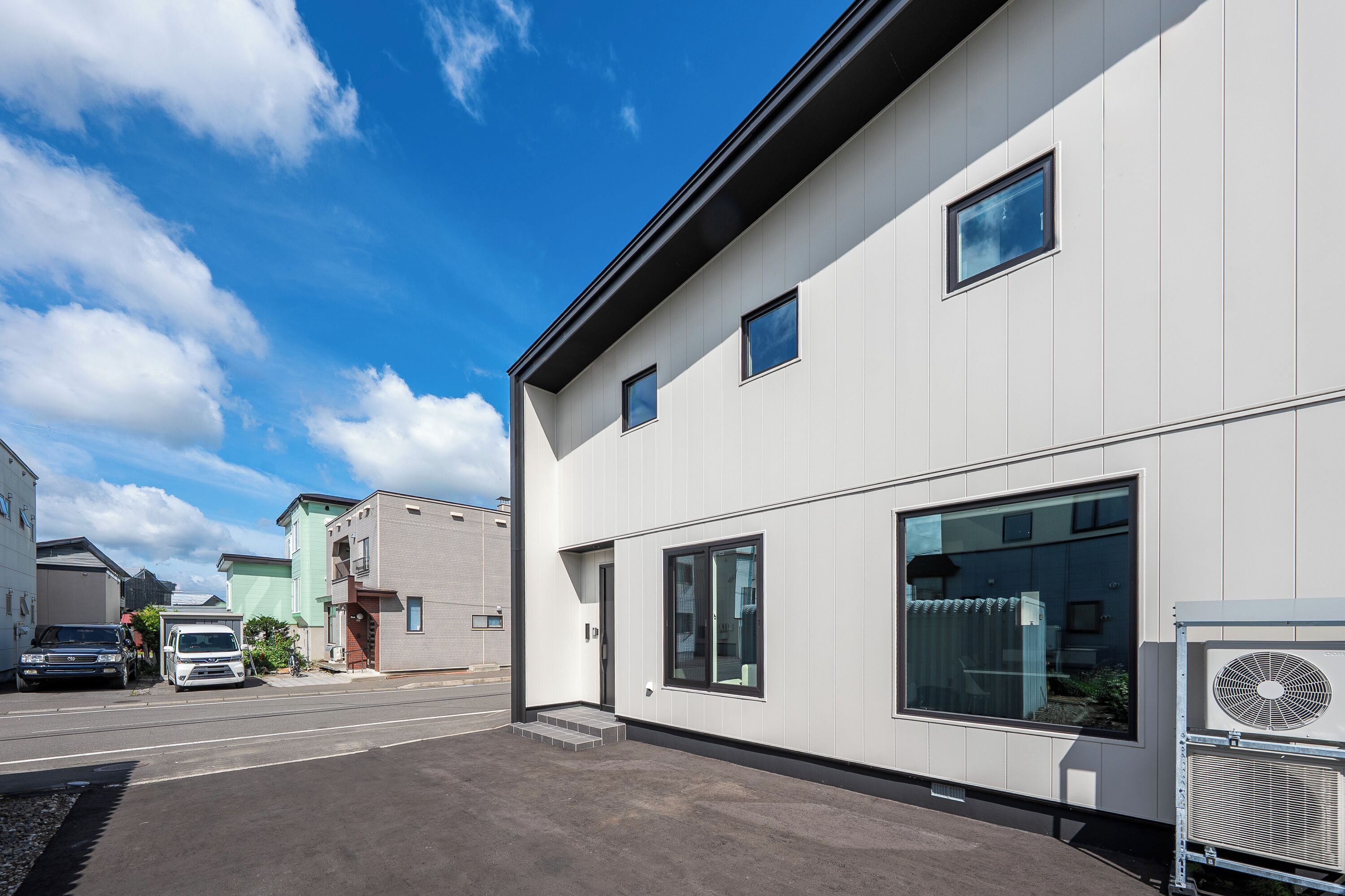 A modern building with large windows and a small air conditioning unit on the side.