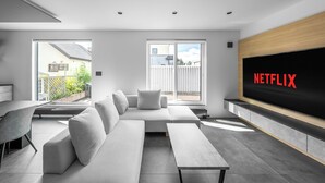 A modern living room with a sofa, a coffee table, and a TV screen displaying "NETFLIX". - S suzukou (Asahikawa)