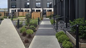 A modern apartment building with a central courtyard, featuring a pathway leading to the entrance. - Stylish 2BR, 2BA Retreat with Yard in Christchurch (Christchurch)