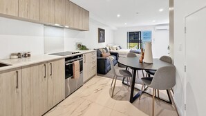 Une cuisine moderne avec des meubles en bois, un coin repas avec une table et des chaises, et un salon avec un canapé et un téléviseur.