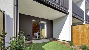 Une maison moderne avec une pelouse bien entretenue, une clôture en bois et une porte-fenêtre coulissante donnant sur une chambre.