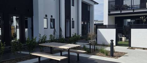A modern building with a courtyard featuring a picnic table and small plants.