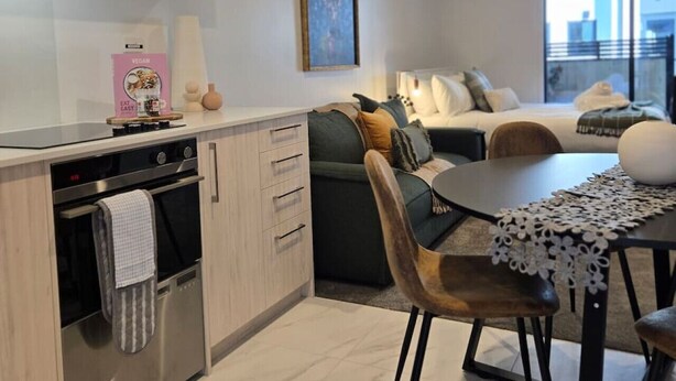 Ett modernt kök med en inbyggd ugn och en matplats med bord och stolar.