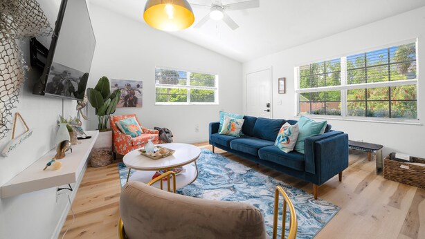Un salon avec un canapé bleu, une table basse ronde et un ventilateur de plafond.