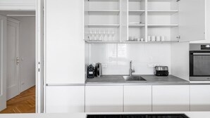 A modern kitchen with white cabinetry, a stainless steel sink, and a built-in oven. - Blueground | Landstraße, balcony, nr Belvedere (Vienna)
