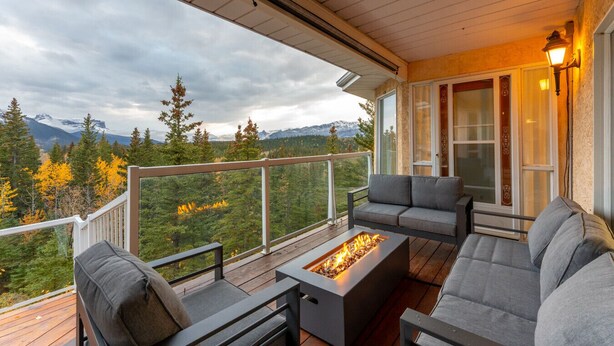A deck with a fire pit, grey sofas, and a view of mountains and autumn trees. - 4,000 SF Luxury Home | 6-BR + 5-BA | 2-minute DRIVE to Jasper National Park (Jasper)