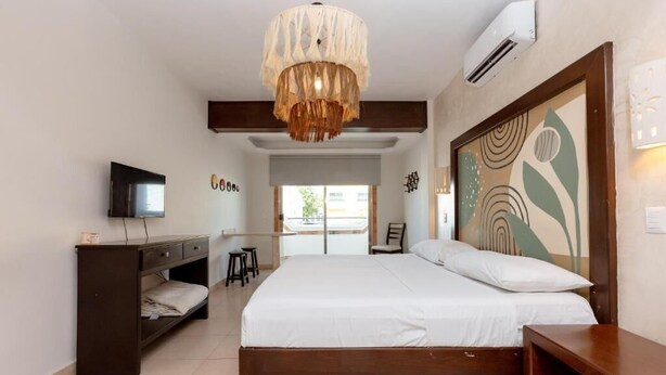 Un dormitorio con cama, escritorio, silla, televisor y decoración en la pared.