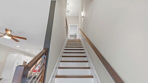 Una escalera de madera con peldaños y barandilla, que conduce a una plataforma con una puerta.